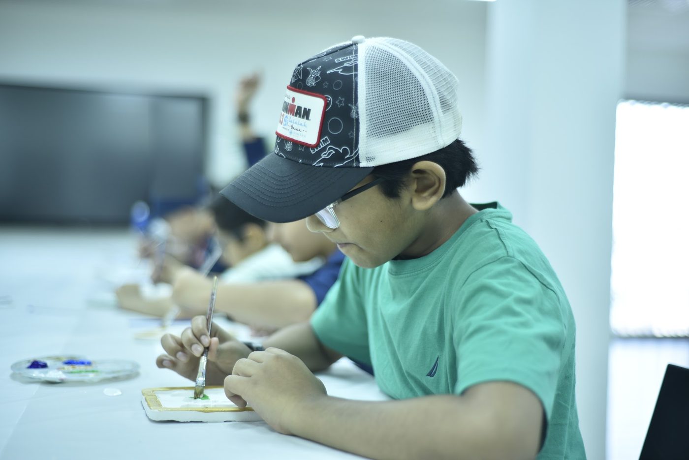 Student painting a framed art piece with a brush during a studio session