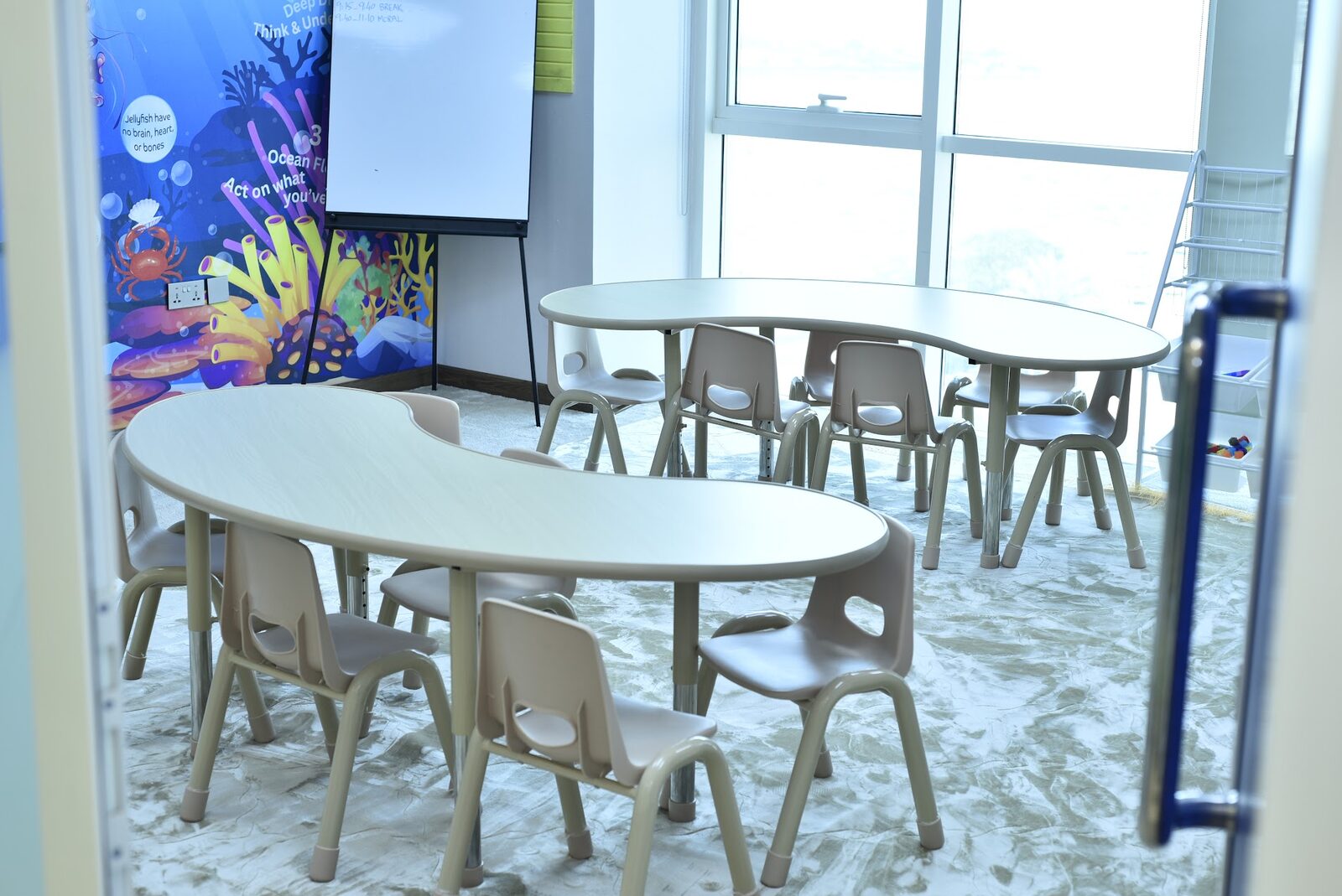 Ocean-themed classroom with kidney-shaped tables and whiteboard