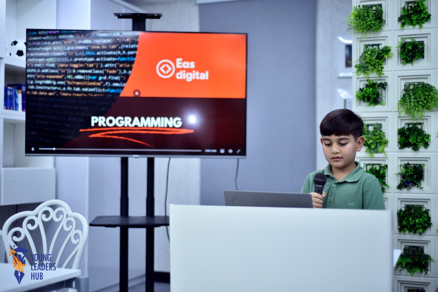 Student presenting his programming project on screen with a microphone at a podium