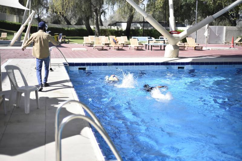 Coach walking the poolside filming the swimmers racing