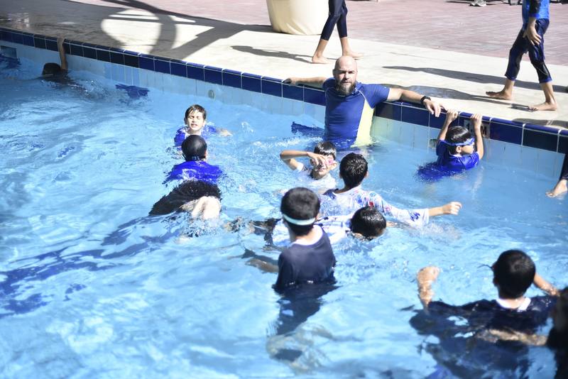 Instructor at the wall while the whole group practises in the pool