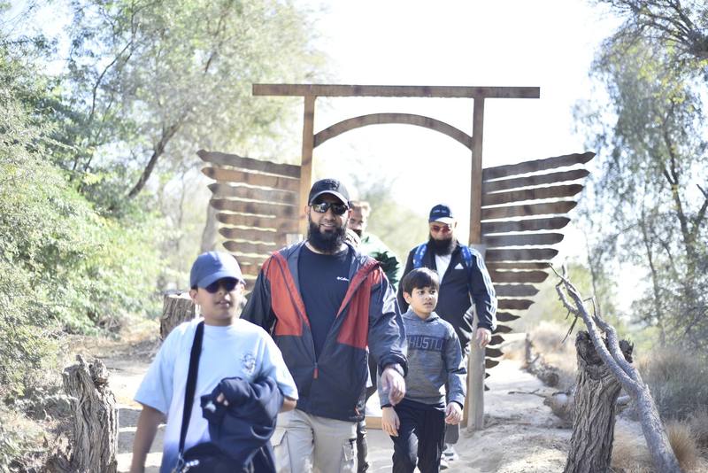Fathers and sons walking through the wooden archway on the trail