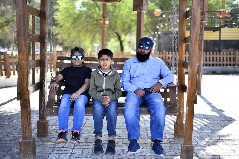 Father and his two sons sitting together on the garden swing