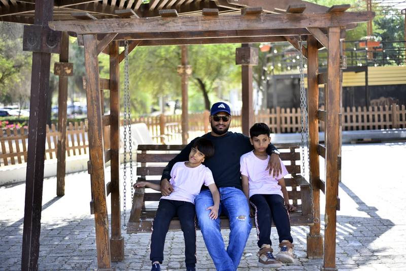 Father with an arm around each of his two sons on the swing