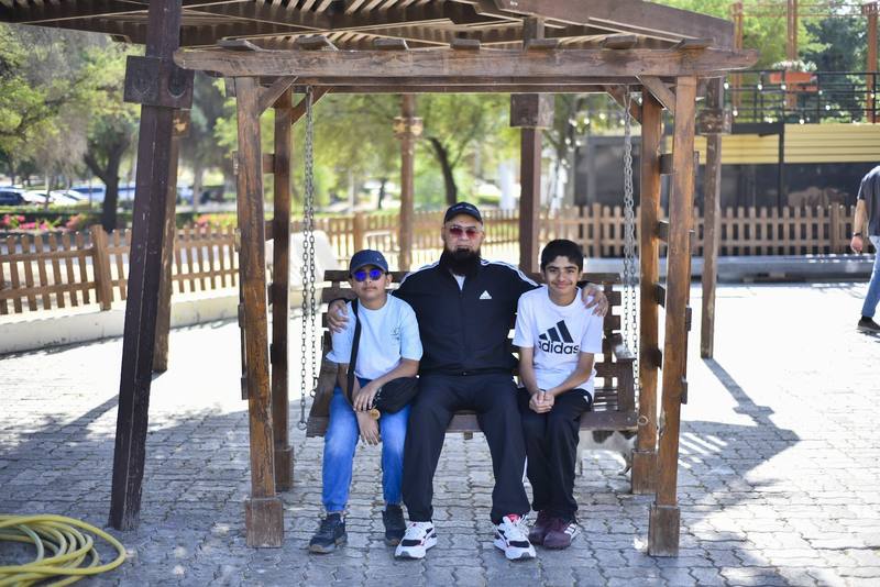 Father and his two sons posing together on the swing