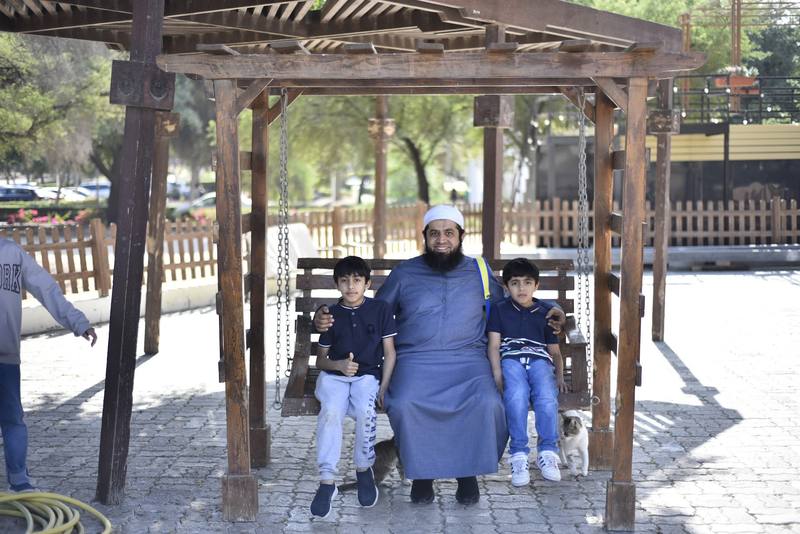 Smiling father seated on the swing with his two young sons