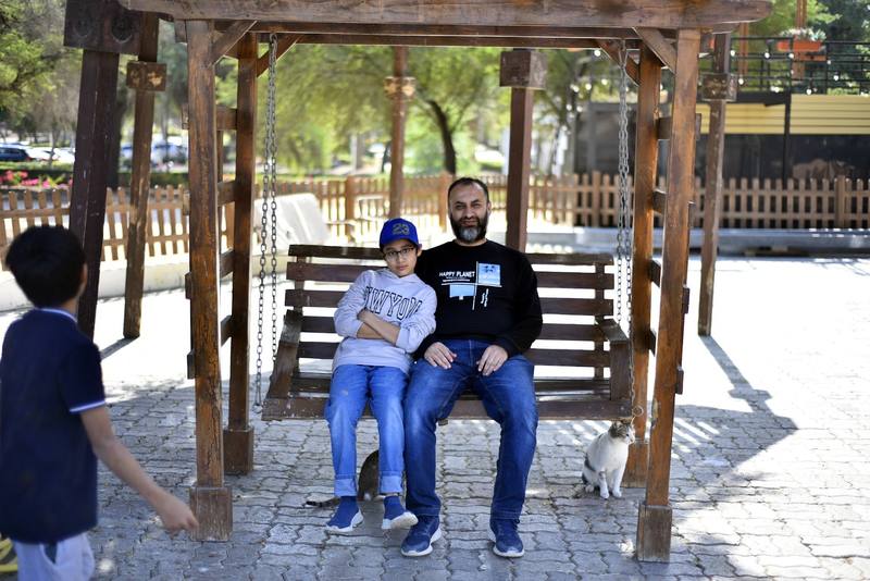 Father and son sitting on the swing with cats resting nearby