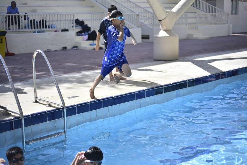 Boy leaping from the poolside into the water