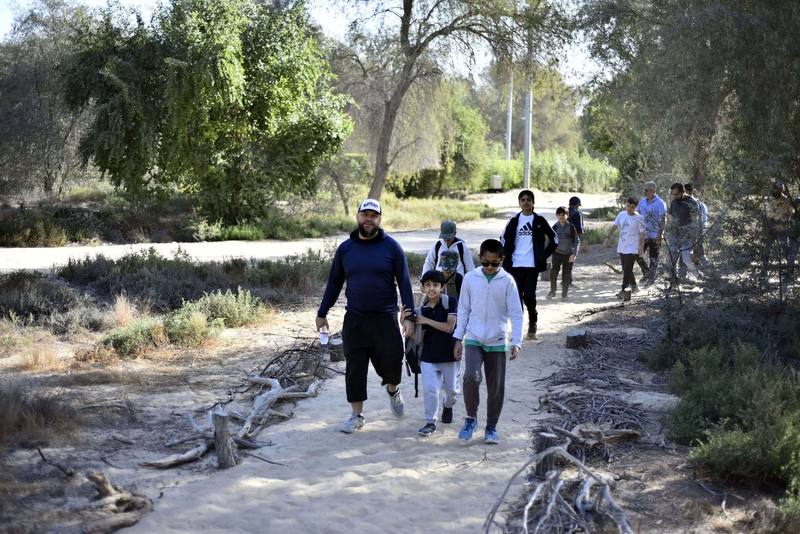 Group walking along the sandy desert trail through the trees