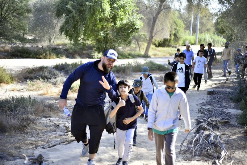 Group leader waving as fathers and sons follow along the trail