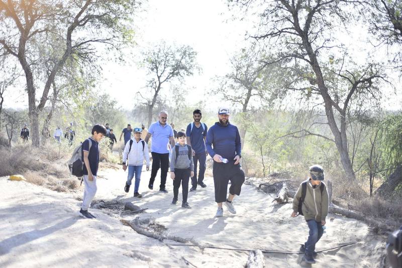 Fathers and sons spread out along the bright sandy trail