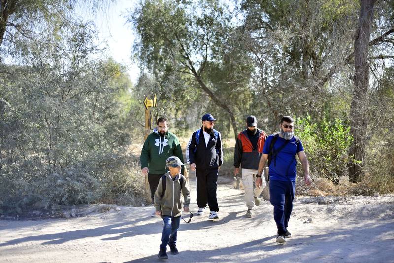 Fathers and a son walking steadily along the sandy trail