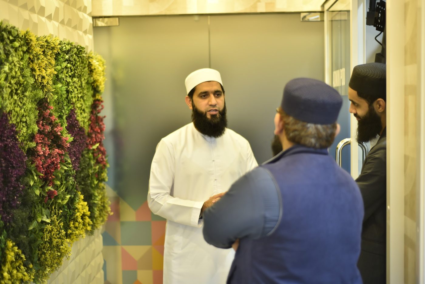A conversation between attendees by the living wall