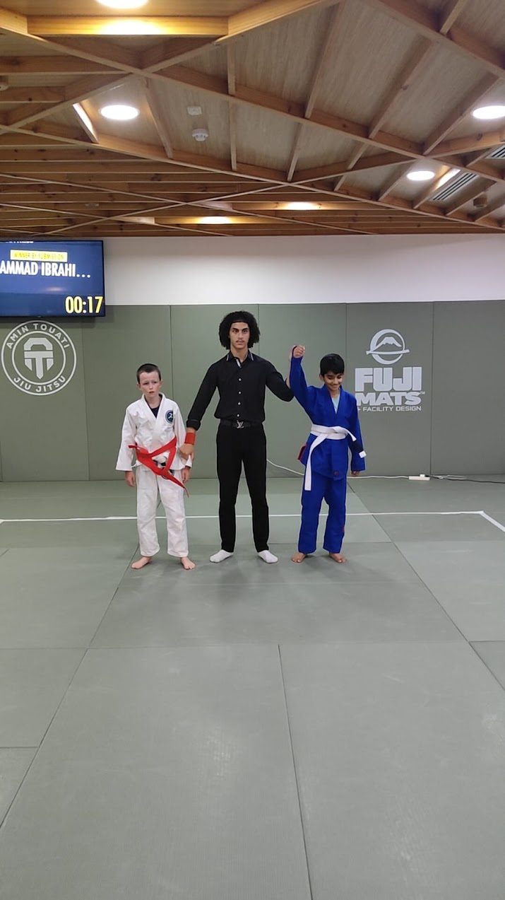 Referee raising a competitor's hand in victory on the mat