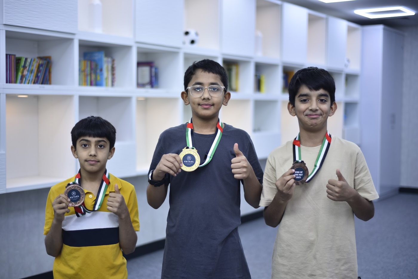 Three medalists giving a thumbs up while holding their medals