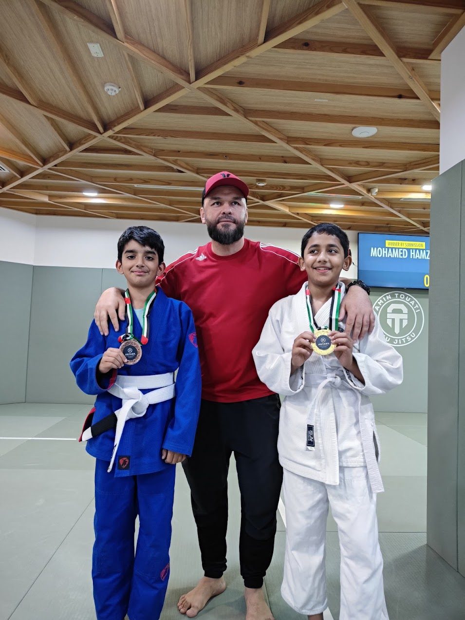 Two medalists posing with their coach after the tournament