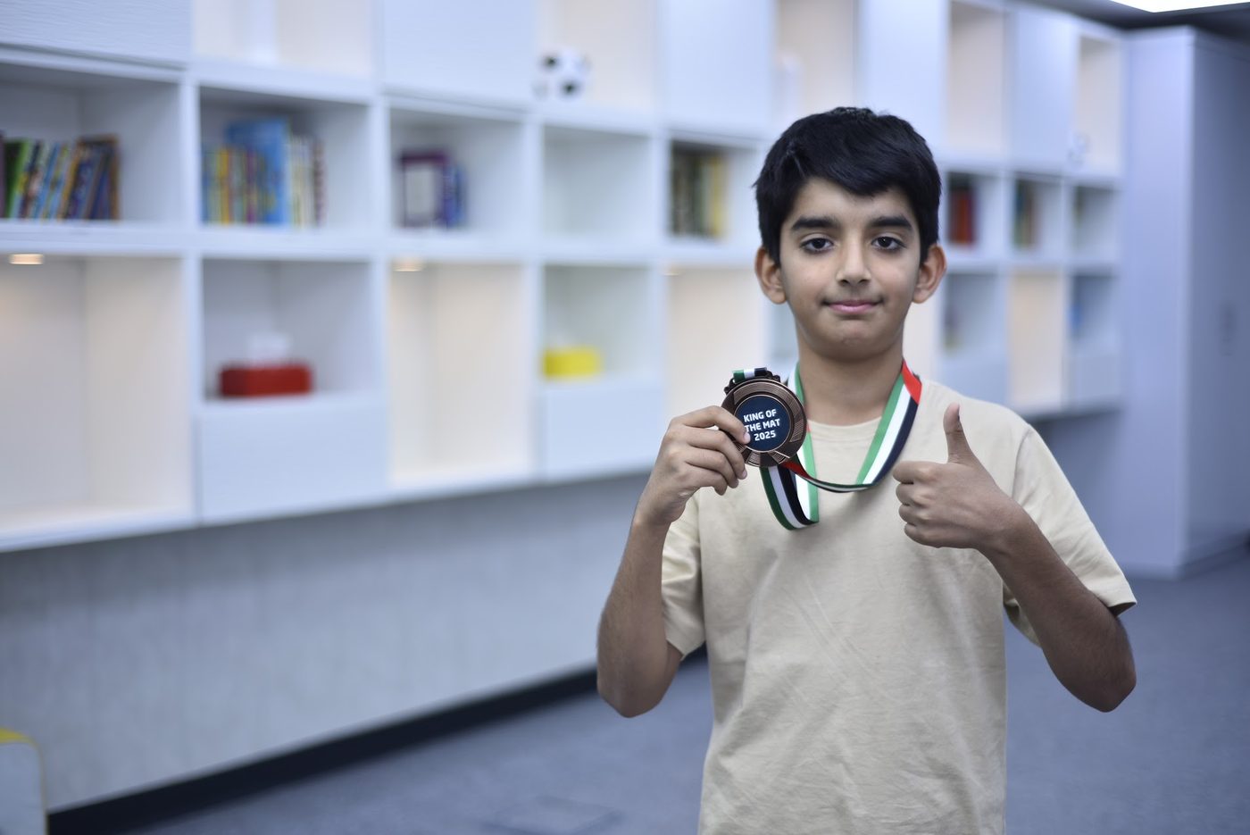 Competitor holding a King of the Mat 2025 bronze medal, giving a thumbs up