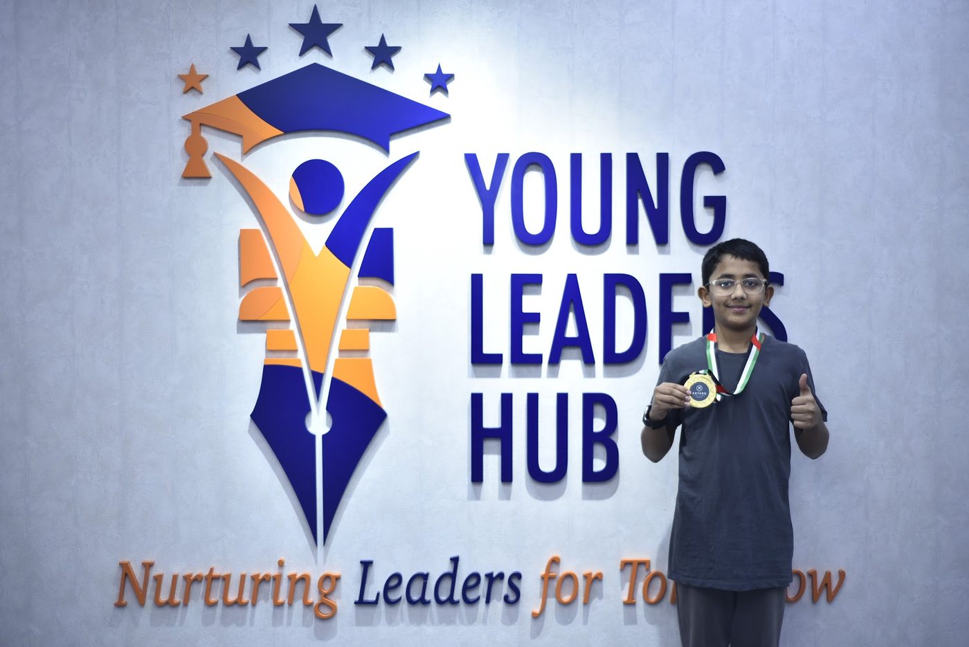 Gold medal winner giving a thumbs up in front of the Young Leaders Hub sign